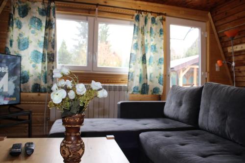 a living room with a couch and a vase of flowers on a table at Chata na Orave so saunou a kúpacou kaďou in Námestovo