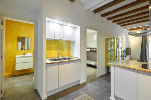 バルセロナにある64 Apartment in a typical Barcelona's old buildingの白いキャビネットと黄色のタイルを用いたキッチン