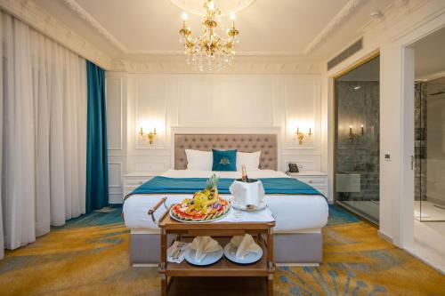 a bedroom with a bed with a tray of fruit on a table at Grand Hotel Belushi in Boge