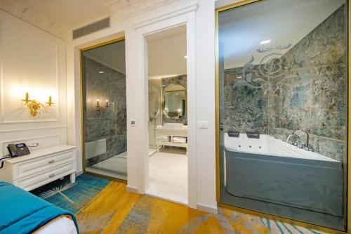 a bathroom with a tub and a large mirror at Grand Hotel Belushi in Boge