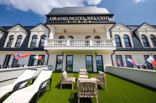 a building with chairs and tables in front of it at Grand Hotel Belushi in Boge