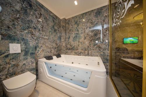 a bathroom with a tub and a toilet and a sink at Grand Hotel Belushi in Boge