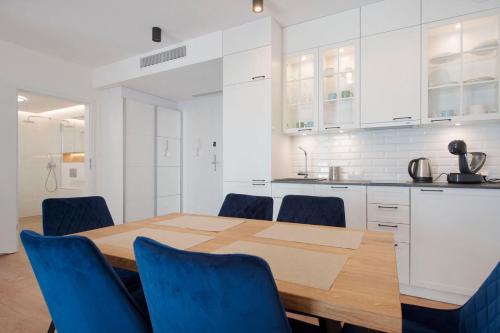 eine Küche mit einem Holztisch und blauen Stühlen in der Unterkunft Apartament Premium PINEA 302 in Pobierowo