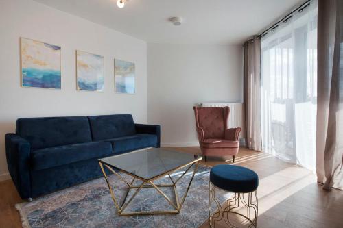 a living room with a blue couch and a glass table at Apartament Premium PINEA 302 in Pobierowo