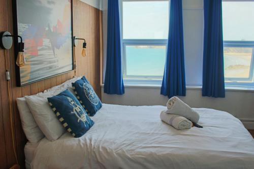 a bedroom with a white bed with blue curtains at St Christopher's Inn Newquay in Newquay