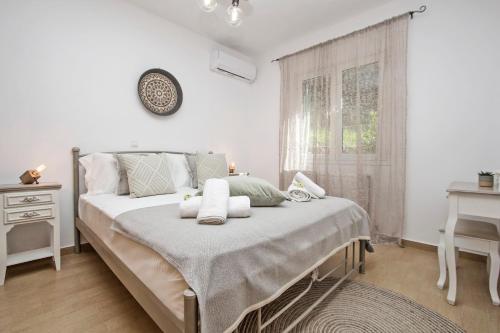 a bedroom with a bed with white sheets and a window at Quercus Villa, Achilleion Palace, Corfu in Perama