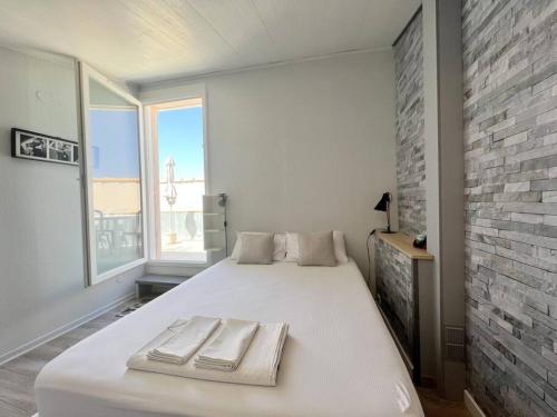 - un lit blanc dans une chambre dotée d'un mur en briques dans l'établissement Appartement 136, Port soleil village naturiste, au Cap d'Agde