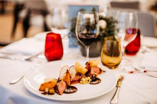 a plate of food on a table with wine glasses at Seehotel am Kaiserstrand in Lochau