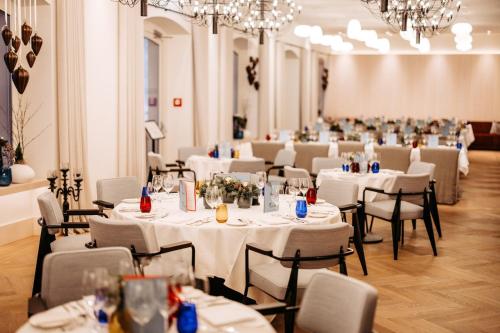 ein Zimmer mit Tischen und Stühlen mit weißem Tischtuch in der Unterkunft Seehotel am Kaiserstrand in Lochau