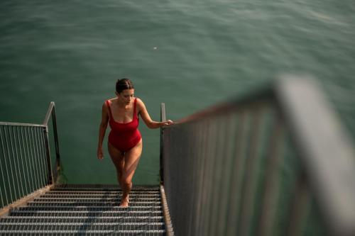 a woman in a red swimsuit walking down a bridge at Seehotel am Kaiserstrand in Lochau