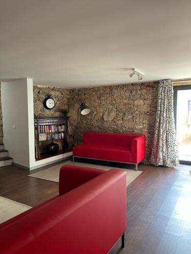 a living room with red furniture and a brick wall at Casa do Caseiro in Outeiro Maior