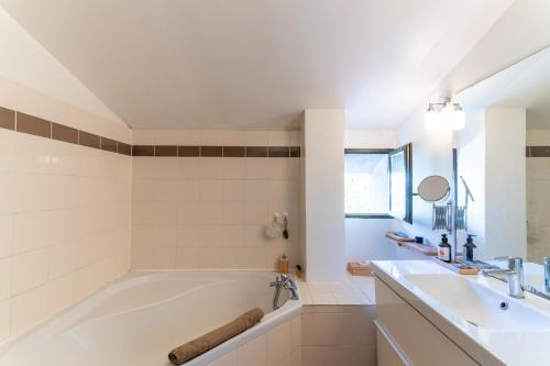 een witte badkamer met een bad en een wastafel bij Santal : maison avec piscine entre terre et mer in Saint-Pargoire