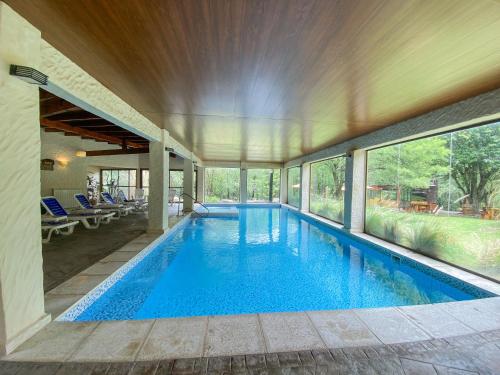 una piscina cubierta en una casa con ventanas en Posada Alma del Arroyo & Spa en Villa General Belgrano