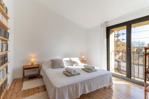 een witte slaapkamer met een bed en een groot raam bij Santal : maison avec piscine entre terre et mer in Saint-Pargoire