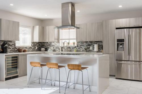 a kitchen with a large white island with three bar stools at Olas Villa by Rove Travel - Home with Heated Pool in Fort Lauderdale