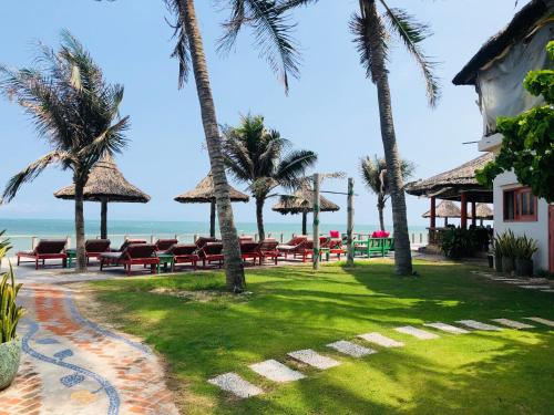 a resort with chairs and palm trees and the ocean at Full Moon Beach Resort in Mui Ne