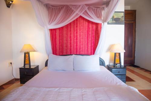 a bedroom with a white bed with a red curtain at Full Moon Beach Resort in Mui Ne