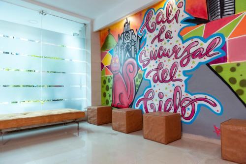 a room with a graffiti wall with a bench and stools at Hotel Plaza Las Américas Cali in Cali