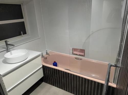 a bathroom with a pink tub and a sink at OYO Stay Inn Shakila in Aberdeen