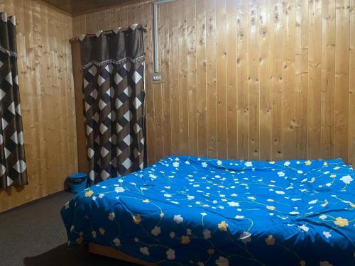 Una cama con una manta azul con flores. en kashmir holidays homestay, en Srinagar