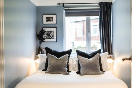 een slaapkamer met een bed met kussens en een raam bij Newport's heart: Steps from shops & local charm! in Newport