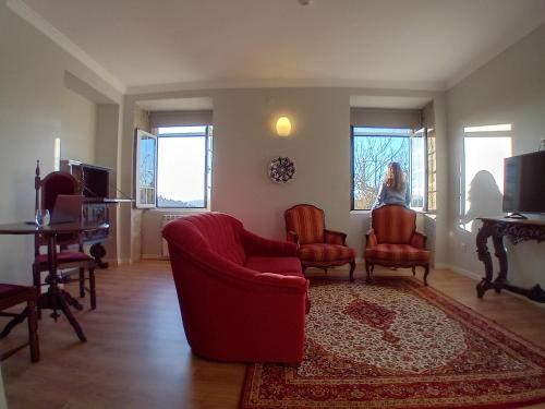 a woman sitting in a living room with chairs and a rug at Quinta de Marzovelos in Viseu