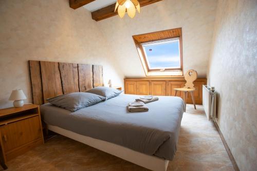 Un dormitorio con una cama grande y una ventana en Le Refuge des Merelles. (accepte les animaux), en Lapoutroie