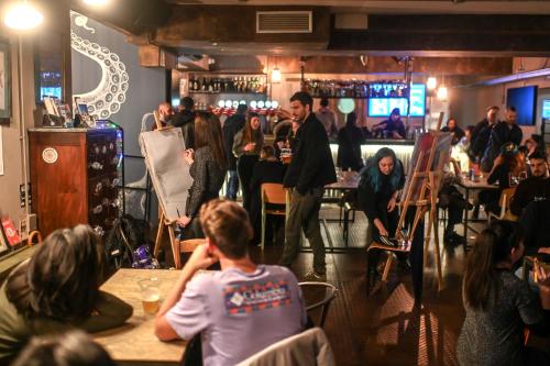 a crowd of people in a bar with a man standing in a room at Ostello Bello Genova in Genova