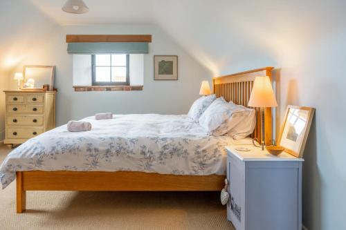 a bedroom with a bed and a table with a lamp at Oyster Barn in Titchwell