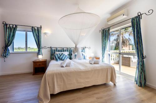 a bedroom with a large bed with blue curtains at Casa Neel in Boliqueime