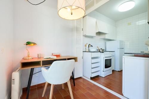a white kitchen with a desk and a white chair at CP 13-A - Calella de Palafrugell in Calella de Palafrugell