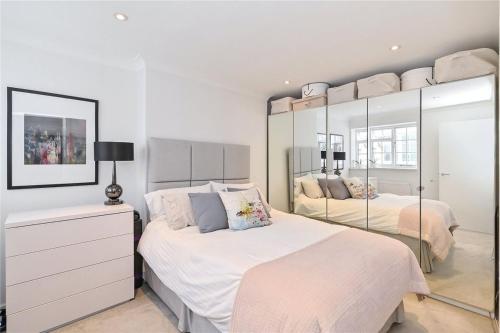 a white bedroom with two beds and a mirror at £4 Million Covent Garden Apartment in London