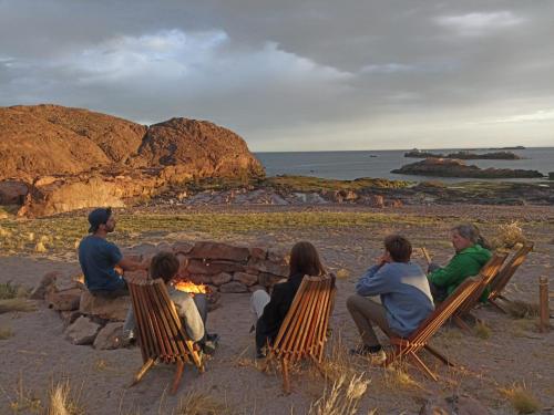 a group of people sitting around a bonfire on the beach at Isla Leones Camps in Camarones