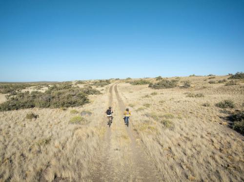 two people riding bikes down a dirt road at Isla Leones Camps in Camarones