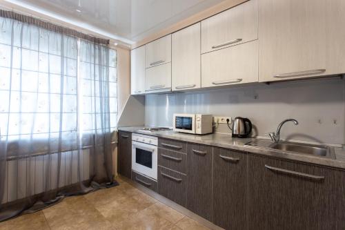 a kitchen with white cabinets and a sink and a microwave at Covent - Garden - Kharkiv in Kharkiv