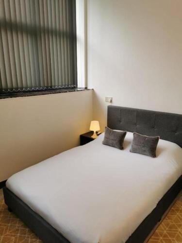1 dormitorio con 1 cama blanca grande y 2 almohadas en Budget Central Serviced Studio Apartment en Sunderland