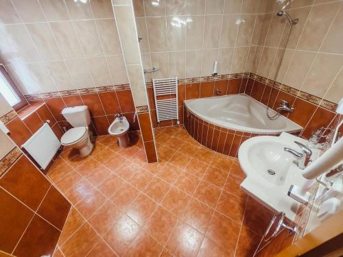 a bathroom with a tub and a toilet and a sink at YURA hotel Čeladná -BAZÉN A SAUNA ZDARMA in Čeladná