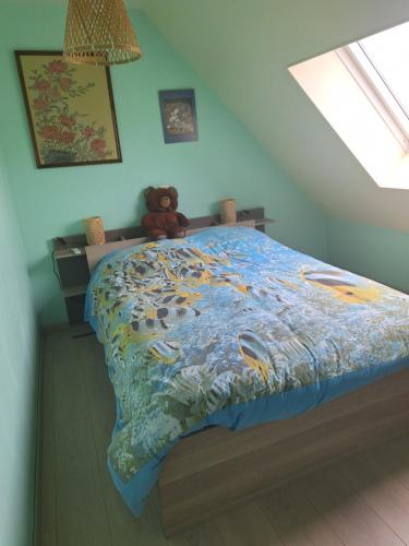 - un ours en peluche assis sur un lit dans une chambre dans l'établissement CHOUETTE MAISON, à La Verrière