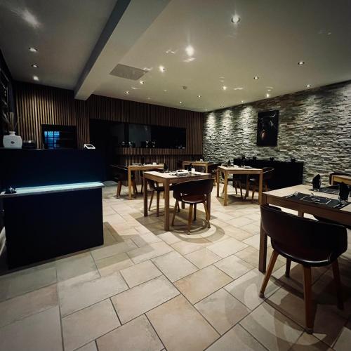 Un restaurante con mesas y sillas y una pared de piedra. en Logis Le Relais de la Voie Sacrée, en Issoncourt