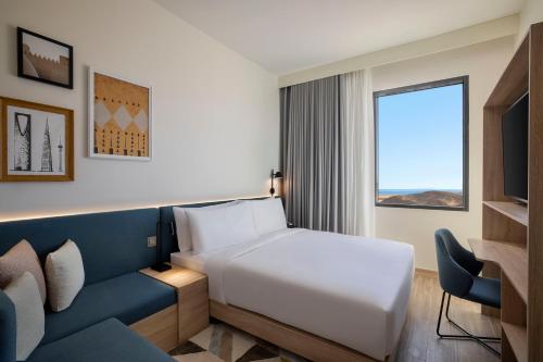 een hotelkamer met een bed en een bank bij Hampton By Hilton Sharma - NC1 in Khuraybah