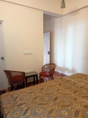 a bedroom with a bed and two chairs and a table at Beechwood Holiday Apartments in Mussoorie