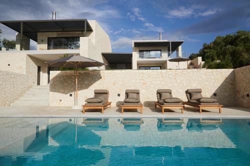 una casa con piscina con sedie e ombrellone di Luxury Stone Houses Corfu a Píthos