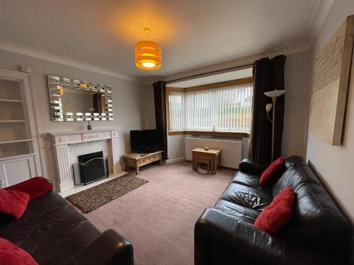 Una sala de estar con un sofá y una chimenea. en 1930s 3Bed House in Quiet Village w/ Large Garden, en Bishopton