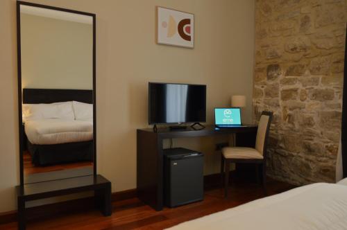 a bedroom with a desk with a bed and a mirror at Hotel Baeza Monumental by eme hoteles in Baeza