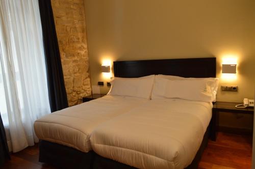 a bedroom with a large bed with white sheets and pillows at Hotel Baeza Monumental by eme hoteles in Baeza