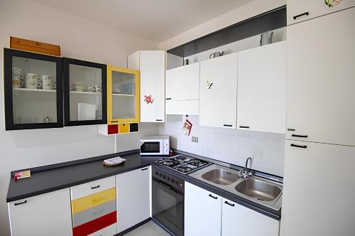 a kitchen with white cabinets and a stove and sink at casa sulla spiaggia in Cala Gonone