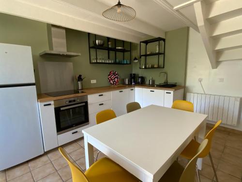 une cuisine avec une table blanche et des chaises jaunes dans l'établissement Maison proche des plages -grand jardin, à Plogoff
