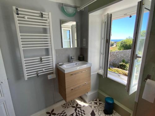 uma casa de banho com um lavatório, um espelho e uma janela em Maison à 500m de la plage em Plogoff