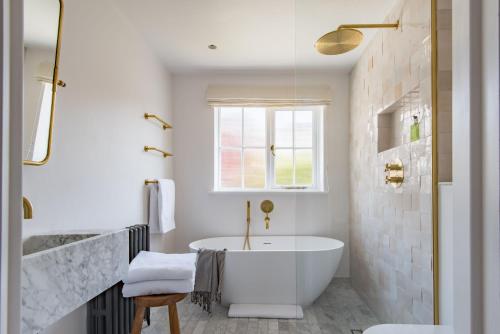 een witte badkamer met een bad en een raam bij The Nomad House - Sea Views Overlooking the Square in Ramsgate