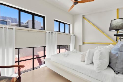 a bedroom with a white bed and large windows at Loft on Hope in Cape Town